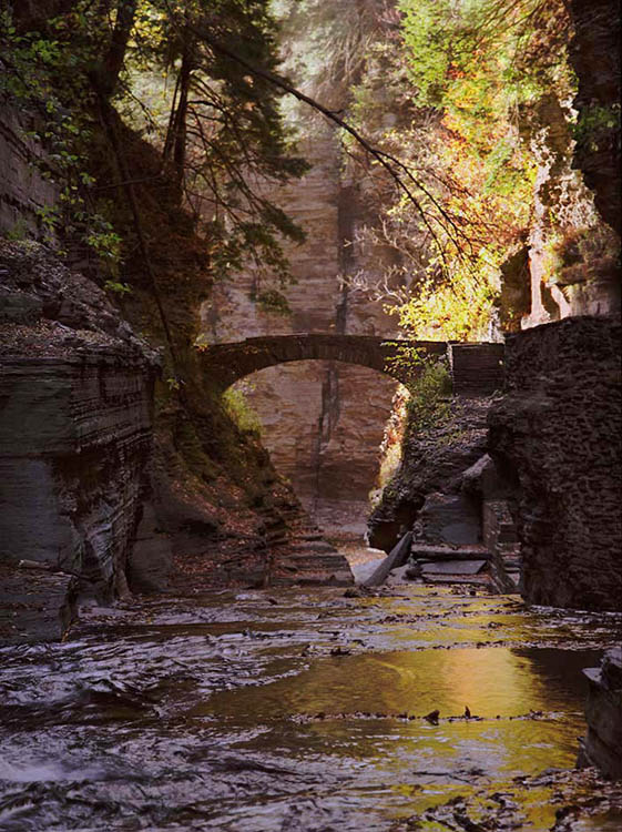 Autumn color reflected in Enfield Creek with stone bridge @ Treman State Park NY