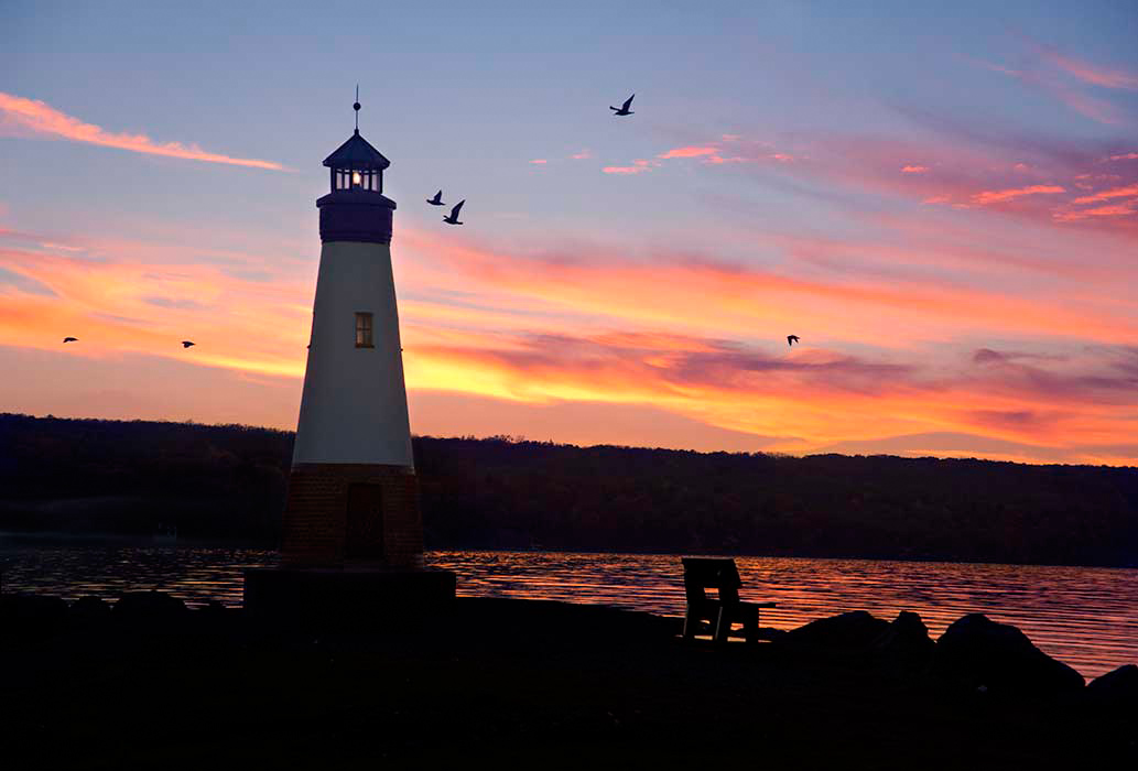 Myers Point Lighthouse at sunset with gulls flying by