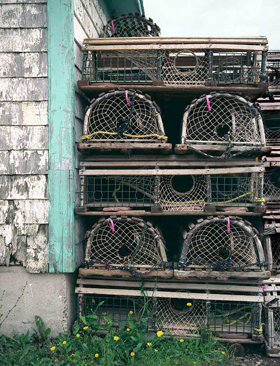 Wooden lobster post stacked beside an old building awaiting their turn in PEI, Canada